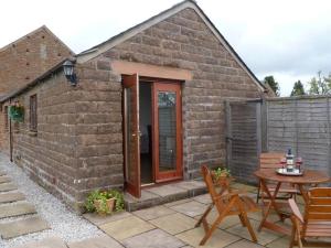 ein kleines Backsteinhaus mit einem Tisch und Stühlen in der Unterkunft Buttercup Cottage in Penrith + 3 Fotos