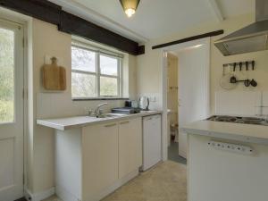 cocina con armarios blancos, fregadero y ventana en The Old Engine House, en Bodmin