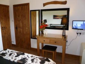 Zimmer mit einem Holzschreibtisch und einem Spiegel in der Unterkunft Buttercup Cottage in Penrith