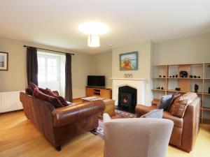 a living room with leather furniture and a fireplace at Dunnottar Woods House in Stonehaven