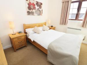 a bedroom with a bed with white sheets and a lamp at Savita Cottage in Girvan