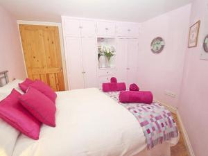 a bedroom with a large white bed with pink pillows at Mithian Cottage in St. Agnes