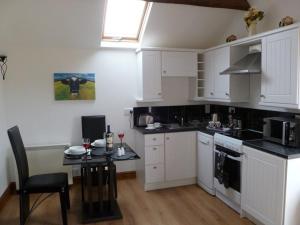 eine Küche mit weißen Schränken und einem kleinen Tisch mit Stühlen in der Unterkunft Buttercup Cottage in Penrith