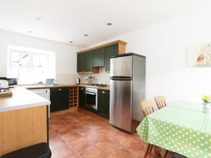 a kitchen with green cabinets and a stainless steel refrigerator at Dunnottar Woods House in Stonehaven
