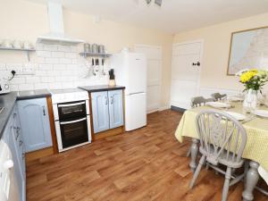 a kitchen with white appliances and a table with a yellow table cloth at Penglanowen Fawr in Rhostie
