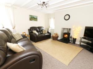 a living room with a leather couch and a fireplace at Penglanowen Fawr in Rhostie