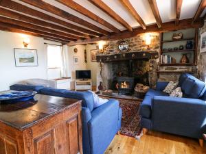 a living room with two blue couches and a fireplace at Chilvery Farm Cottage in Okehampton