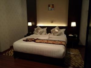 a bedroom with a large bed with white sheets and pillows at Sherar Addis Hotel in Addis Ababa