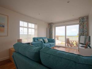 a living room with a blue couch and a television at Kittiwake in Crantock