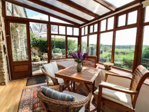 a conservatory with a table and chairs and windows at Chilvery Farm Cottage in Okehampton