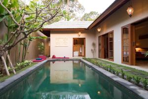 a swimming pool in front of a house at Ajanta Villa in Sanur