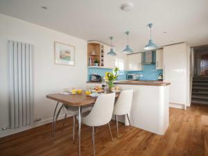a kitchen with a wooden table and white chairs at Kittiwake in Crantock