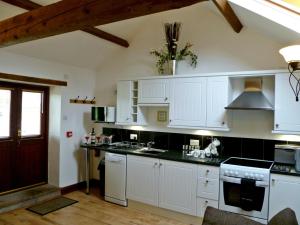 a kitchen with white cabinets and black counter tops at Daisy Cottage in Penrith +4 photos