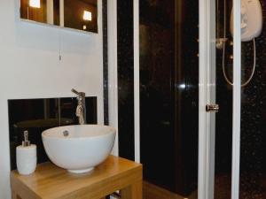 a bathroom with a white bowl sink on a wooden table at Daisy Cottage in Penrith