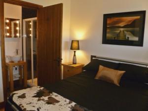 a bedroom with a black bed and a bathroom at Daisy Cottage in Penrith