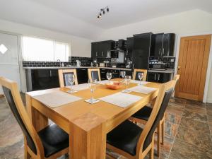 a kitchen with a wooden table with wine glasses at Felin Manaw in Bryngwran