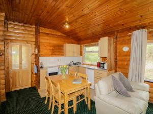 a living room with a table and a kitchen at Eagle Lodge in Strathpeffer
