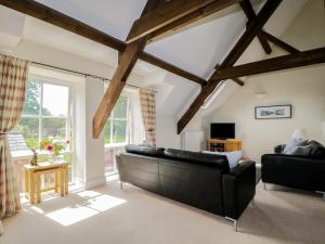 ein Wohnzimmer mit einem schwarzen Sofa und einem Fenster in der Unterkunft Carpenters Cottage in Cockermouth