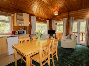 a kitchen and living room with a wooden table and chairs at Eagle Lodge in Strathpeffer +4 photos