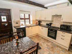 a kitchen with white cabinets and a table with a bottle of wine at 1 The Stables in Clitheroe