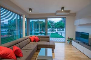 ein Wohnzimmer mit einem braunen Sofa und roten Kissen in der Unterkunft CAISA- luxury apartment 20 m from the sea in Zadar