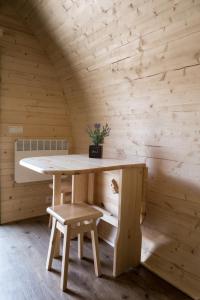 a table in a wooden room with a bench and stool at Leaf Du Nord in Dirbach