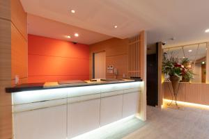 a kitchen with an orange wall and a counter at Terrace Kiyomizu Kyoto in Kyoto