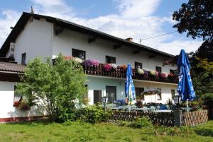 ein weißes Haus mit Sonnenschirmen und Stühlen davor in der Unterkunft Gasthof Waldwirt in Sankt Kanzian am Klopeiner See