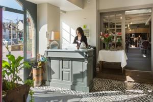 una mujer hablando por teléfono en un mostrador en una tienda en Logis Hôtel Le Beaulieu, en Beaulieu-sur-Dordogne