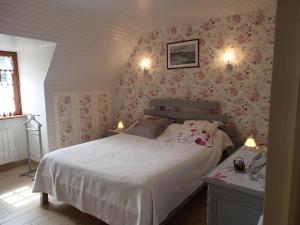 una camera da letto con un letto e carta da parati floreale rosa di Chambre d'Hôtes Broualeuc a Saint-Potan