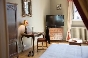 a bedroom with a bed and a desk with a television at Logis Hôtel Le Beaulieu in Beaulieu-sur-Dordogne