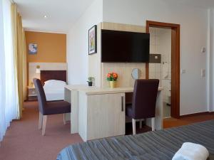 a hotel room with a desk with two chairs and a television at Hotel Denbu Restaurant & BAR in Hamburg