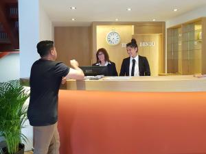 a man standing in front of a reception desk with two people at Hotel Denbu Restaurant & BAR in Hamburg
