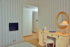 Cette chambre comprend un bureau avec un miroir. dans l'établissement Grand Hotel Menaggio, à Menaggio