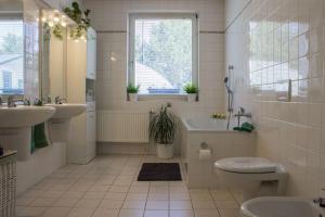 een badkamer met 2 wastafels, een bad en een toilet bij Vila Les Kralovstvi in Nemojov