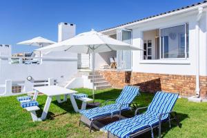 a table and two chairs and an umbrella in a yard at 16 Mile View in Yzerfontein
