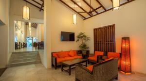 - un salon avec des oreillers orange, une table et des chaises dans l'établissement Pelwehera Village Resort, à Dambulla