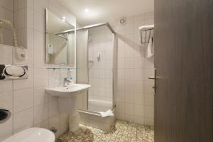 ein Bad mit einem Waschbecken, einem WC und einer Dusche in der Unterkunft Hotel Schumacher Düsseldorf in Düsseldorf