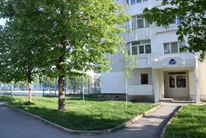 a white building with a tree in front of it at Apartament ALBATROS in Mangalia