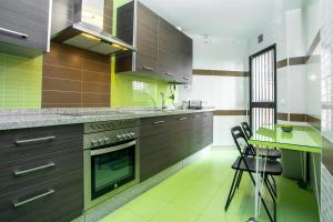マラガにあるLivemalaga Apartment & Parkingのキッチン(茶色のキャビネット、テーブル、椅子付)
