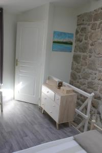 a bedroom with a bed and a dresser and a stone wall at Dans un écrin de Nature in Montclar