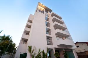un edificio alto y blanco con palmeras delante en The Beach Apartments en Negombo