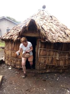 Una mujer está sentada en una cabaña de paja en Machame Nkweshoo Cultural Tourism en Machame