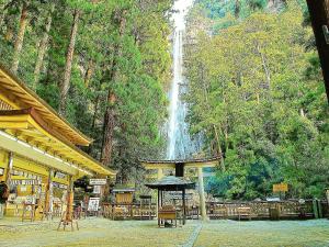a waterfall in the background of a restaurant with a table and umbrella at 小さなペンション Branchee in Kushimoto