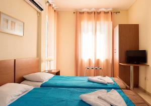 1 Schlafzimmer mit 2 Betten mit blauer Bettwäsche und einem TV in der Unterkunft Stefanakis Hotel & Apartments in Varkiza