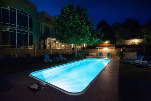 a swimming pool in a yard at night at Bruxelles Guesthouse Craiova in Craiova