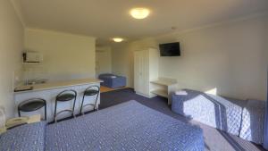 a room with a bed and a kitchen with a sink at Heritage Lodge Motel in Charters Towers