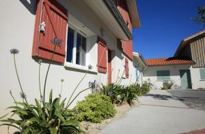 a building with red shutters and plants in a courtyard at Residence Plage Oceane in Biscarrosse-Plage