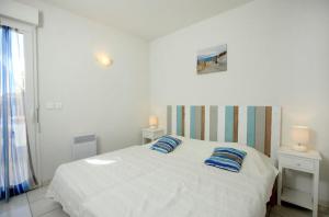 a bedroom with a white bed with two blue pillows at Residence Plage Oceane in Biscarrosse-Plage