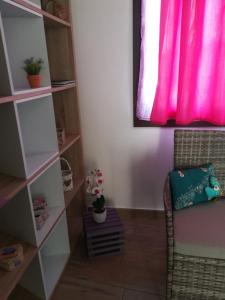une chambre avec une chaise et une fenêtre rose dans l'établissement Piccolo accogliente monolocale, à Siniscola